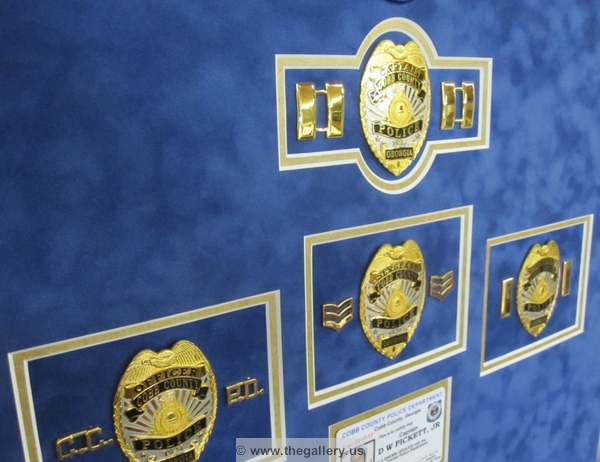 Detail view of Cobb County Police Department retirement shadow box with police badges, patches, ID cards and lapel pins.






The Gallery at Brookwood
www.thegallery.us
770-941-3394
Your Custom Framing Expert
Picture Framing Examples
Custom Framing Examples
Shadowbox Examples
IMG_2838